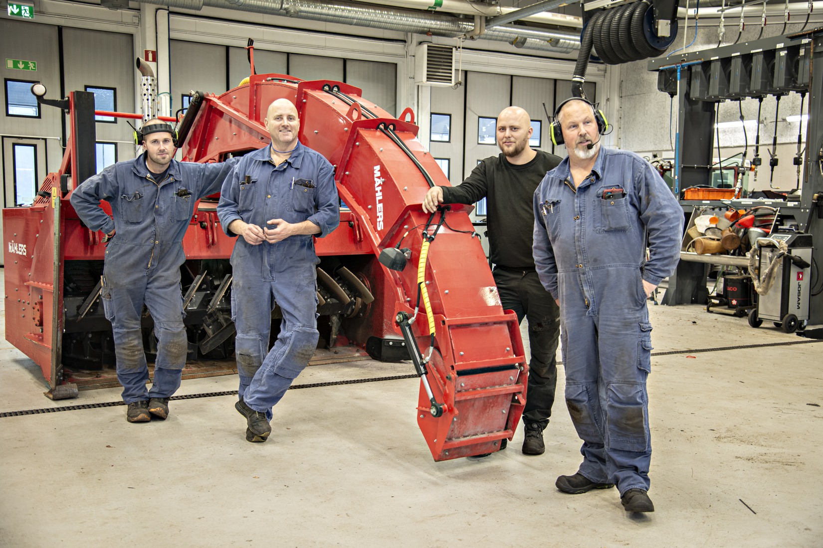 Gruppbild på de fyra reparatörerna Nicklas Lundberg, Jörgen Westring, Kim Anderssen och Freddie Lundberg framför en röd maskin.