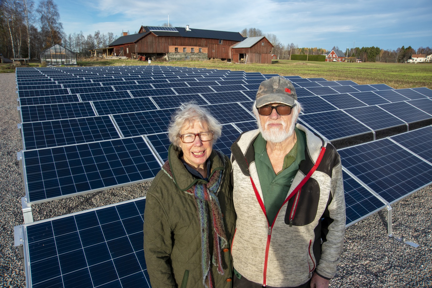 Helge och Marianne Berglund framför solcellerna som sitter på åkern på deras gård.