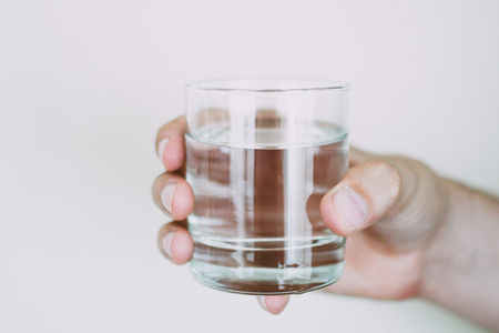 En person håller i ett vattenglas.