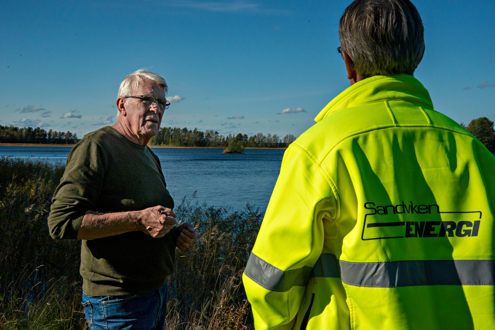 Två män samtalar med Storsjön i bakgrunden.