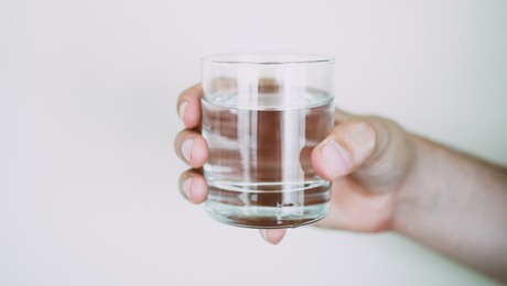 En person håller i ett vattenglas.